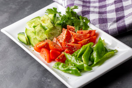 Salad with tomatoes, cucumbers and greens on a white plateの写真素材