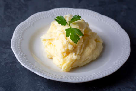 Mashed potatoes with parsley on a white plate on a dark backgroundの写真素材