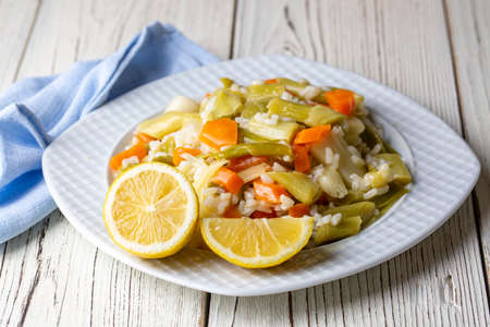 Risotto with vegetables and lemon on a white wooden background.の写真素材