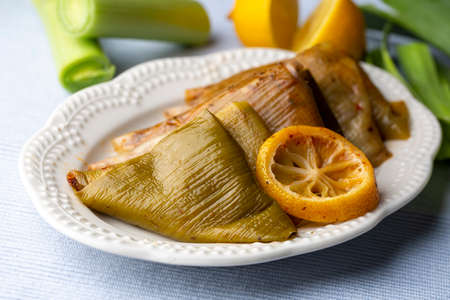 Baked artichoke with lemon and lemons on white plateの写真素材