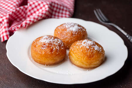Cottage cheese buns with powdered sugar on a white plate.の写真素材