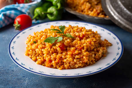 Bulgur with vegetables in a plate on a blue concrete background.の写真素材