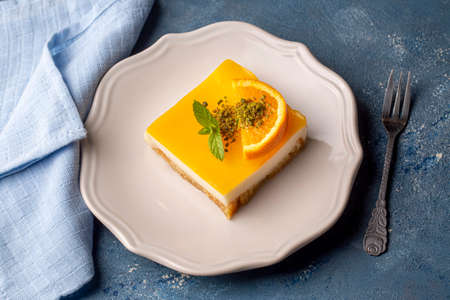 Piece of orange cheesecake with mint on a blue background.の写真素材