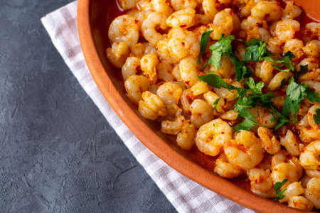 Gnocchi with shrimps and tomato sauce in a clay bowl on a dark concrete background.の写真素材