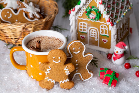 Cup of hot chocolate with gingerbread man, gingerbread house and Christmas decorations on wooden backgroundの写真素材