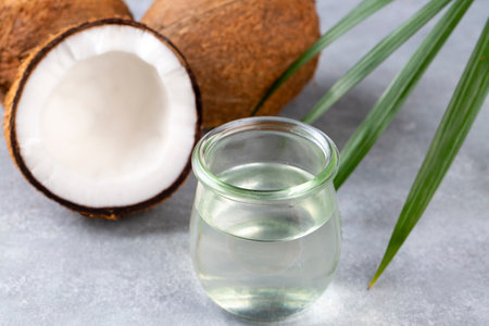 Bottle of coconut oil and fresh coconuts with palm leaf