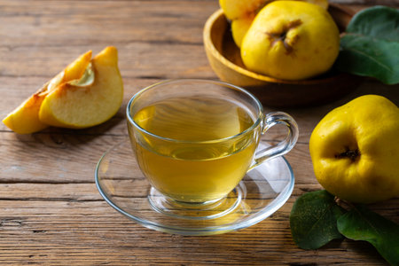 Hot quince tea in transparent teapot with fresh fruits on wooden tableの写真素材