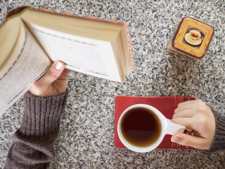 Girl drinking tea and reading a bookの写真素材