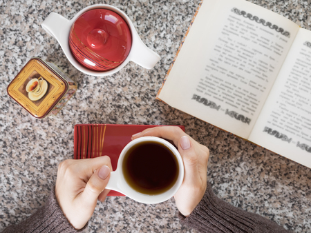 Girl drinking tea and reading a bookの写真素材
