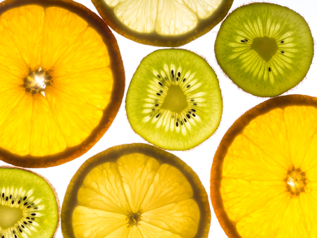 Several slices of lemon, orange and kiwifruit on a white backgroundの写真素材