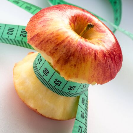 Tape measure wrapped around apple on a white backgroundの写真素材