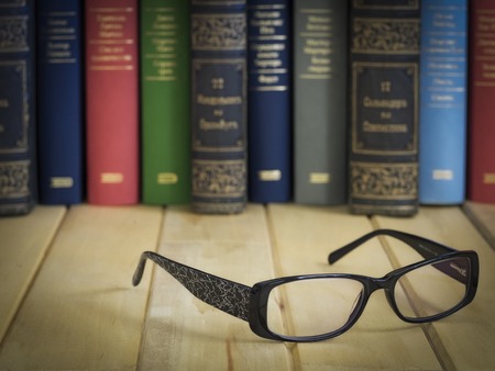 Women glasses in front of several books on the tableの写真素材