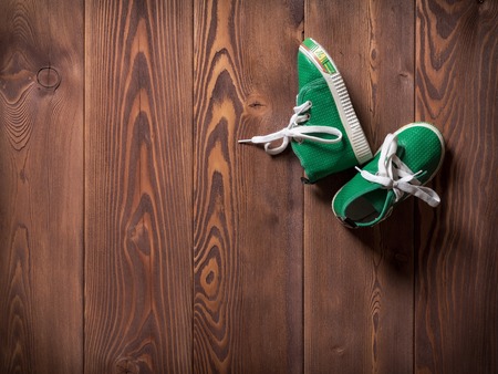 Pair of green children's sneakers on the wooden floorの写真素材