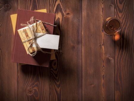 Top view on the pile of books and gift box with sticker for customer's note lying on the tableの写真素材