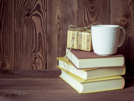 View on the pile of books, cup of tea and gift box lying on the wooden tableの写真素材