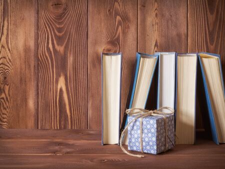 View on the pile of books and gift box lying on the wooden tableの写真素材