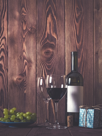 Bottle of wine, wineglasses, grape and gift box on wooden table. Retro style. Dark tonedの写真素材