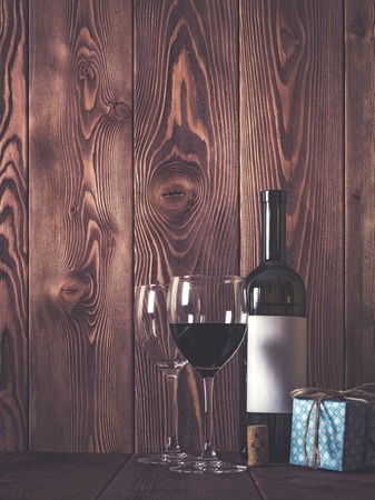 Bottle of wine, wineglasses and gift box on wooden table. Retro style. Dark tonedの写真素材