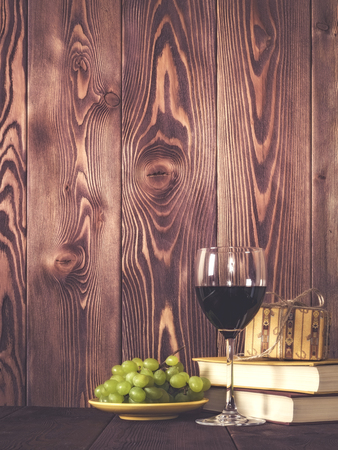 Wineglasses, grape and gift box on wooden table. Retro style. Dark tonedの写真素材