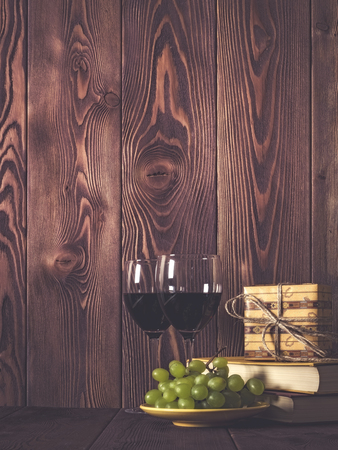 Wineglasses, grape and gift box on wooden table. Retro style. Dark tonedの写真素材