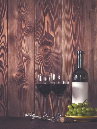 Bottle of wine, wineglasses and grape on wooden table. Retro style. Dark tonedの写真素材