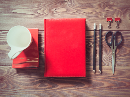 Top view on the desktop with notebook, scissors, cup, saucer and pencilsの写真素材