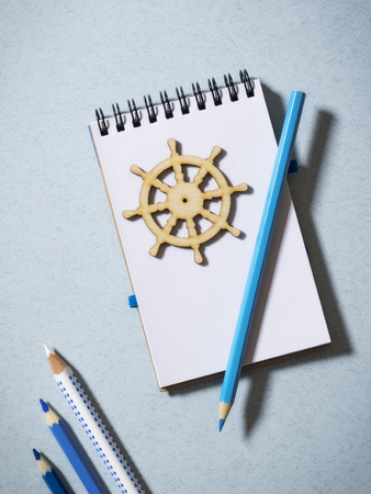Notebook, pencils and some wooden images on the tableの写真素材