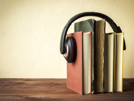 Concept of audiobook. Books on the table with headphones put on themの写真素材