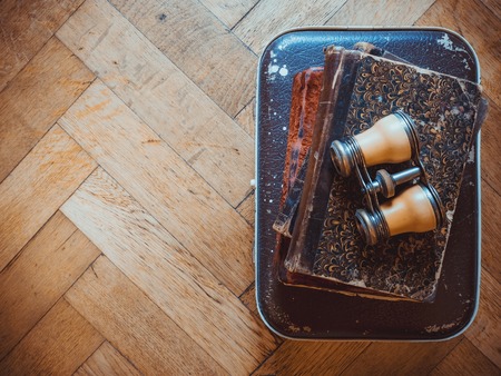 Vintage books and binoculars on an old suitcase. Vintage color. Top viewの写真素材