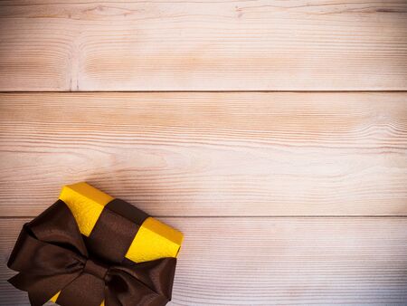 Gift box in glittery paper with bow on wooden board. Holidays conceptの写真素材