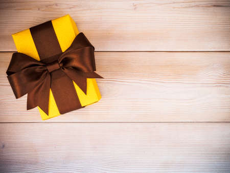 Birthday present with brown satin tape on wooden board. Holidays conceptの写真素材