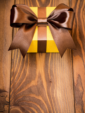 Birthday present with brown satin tape on wooden board. Holidays conceptの写真素材