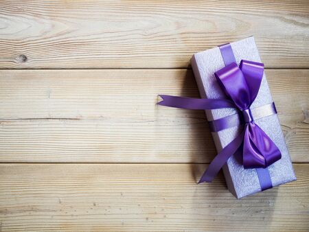 Gift box in glittery paper with bow on wooden board. Holidays conceptの写真素材