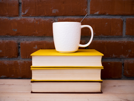 View on the pile of books and cup of tea lying on the wooden tableの写真素材