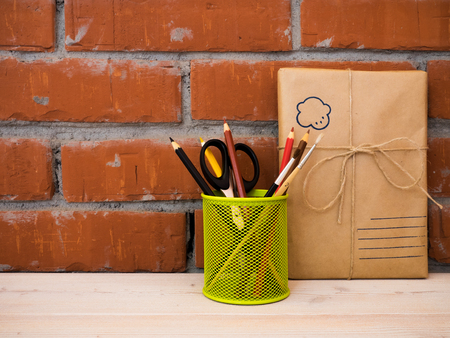 Still life with packed gift and colored pencils on wooden table over brick backgroundの写真素材