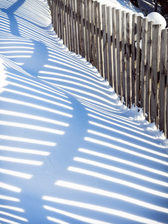Wavy shadow from a wooden fence on snowdriftsの写真素材