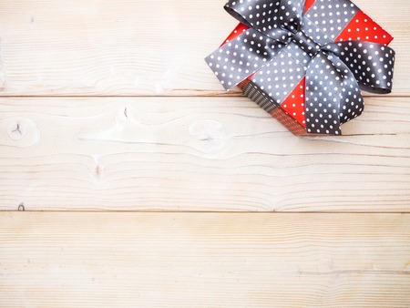 Gift box in glittery paper with bow on wooden board. Holidays conceptの写真素材