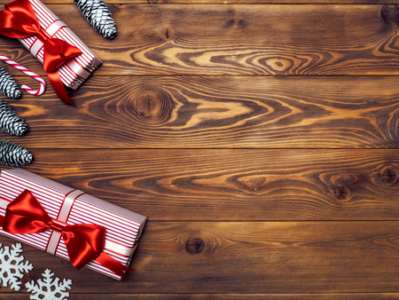 Gift boxes with pine cones, snowflakes and lollypop on wooden board. Holidays conceptの写真素材