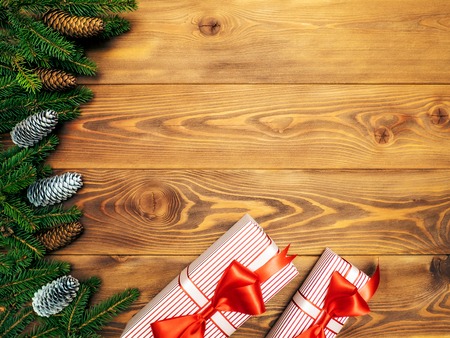 Christmas composition. Fir branches with cones along with gift boxes on the wooden background. Top view. Holiday conceptの写真素材