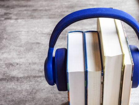 Concept of audiobook. Books on the table with headphones put on themの写真素材