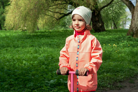 Cute girl is walking in a beautiful green park.の写真素材