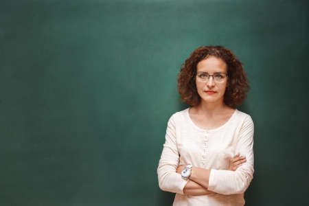 Portrait of a female teacher near the school blackboardの写真素材