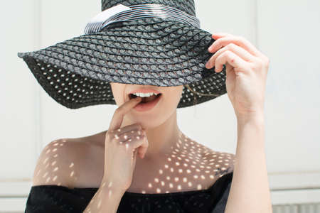 Young girl dying her finger in a way with a hat in the sunの写真素材