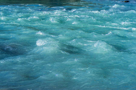Icy cold water of glacier lake stream. Cold blue water stream closeup. Abstract water background. Rapid flow of cold waterの写真素材