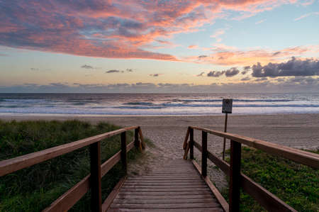 Sunrise ocean beach. Sea beach wooden walkway, path entrance. Sandy ocean beach on sunrise, sunsetの写真素材