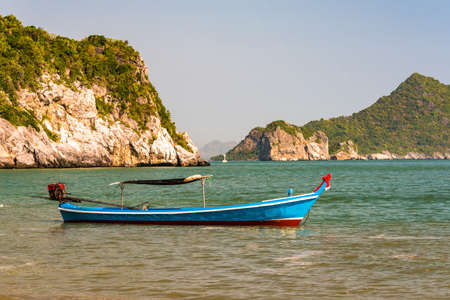Colorful decorated traditional Thailand boat on shoal with sunny sea and island on the background. Kui Buri, Leam Sala, Thailandの写真素材