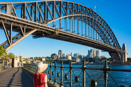 Woman in bright top and hat against Sydney Harbour Bridge on the background. Tourist destination...