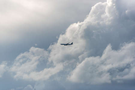 Plane flying in the sky against stormy clouds on the backgroundの写真素材