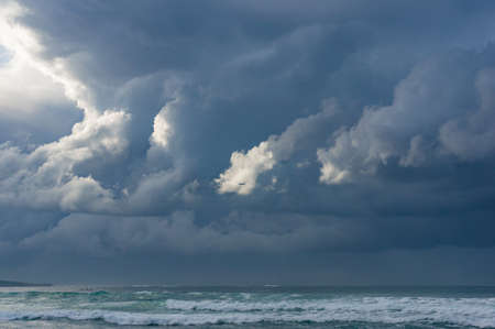 Landscape with stormy ocean and grey clouds with flying airplaneの写真素材
