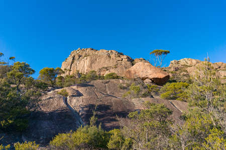 Looking up at mountain steep slope with blue sky on the background. Nature mountain background. Mount Amos, Freycinet National Park, Tasmania, Australiaの写真素材